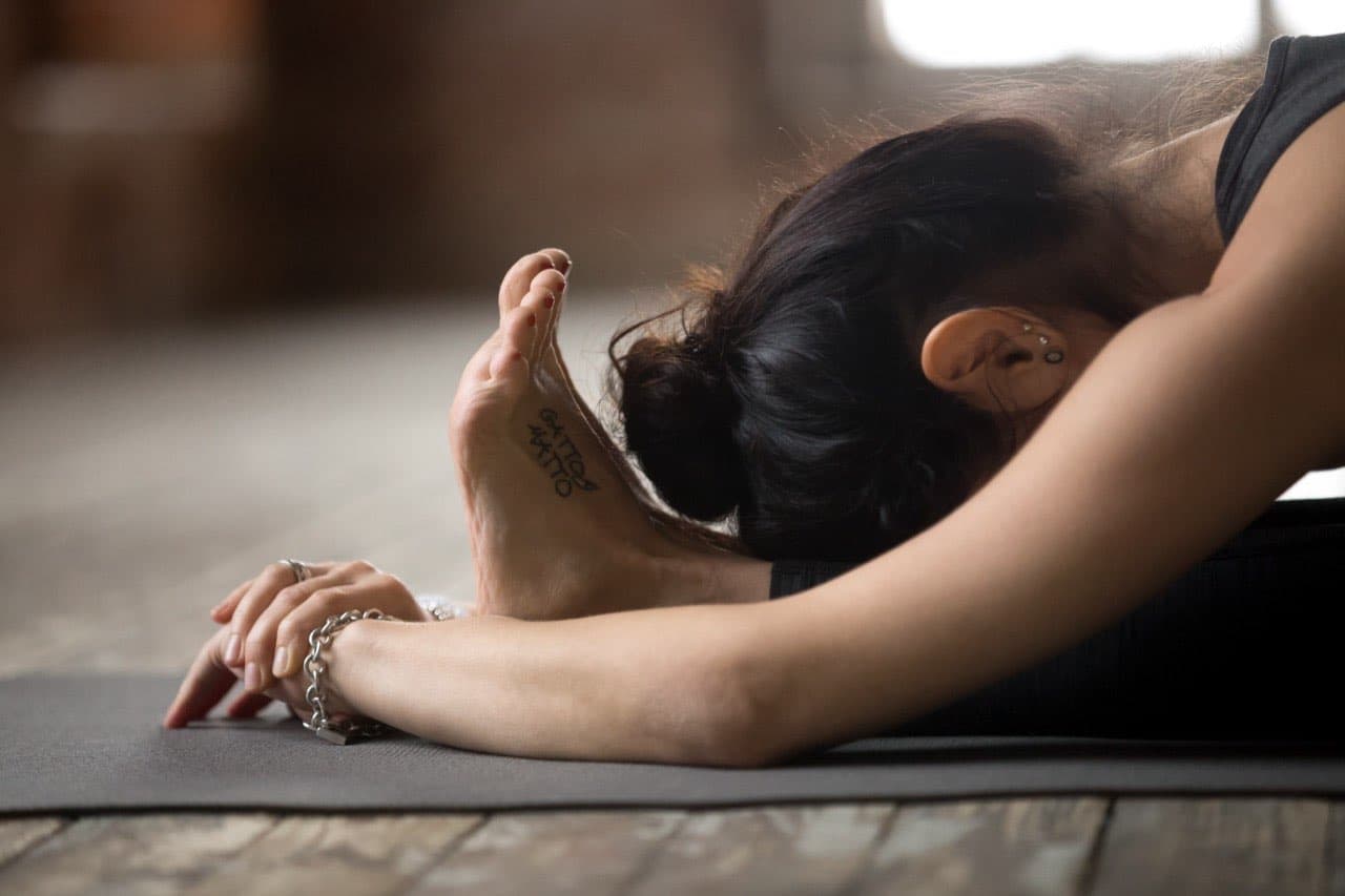 Frau in ruhiger Vorbeuge auf der Yogamatte